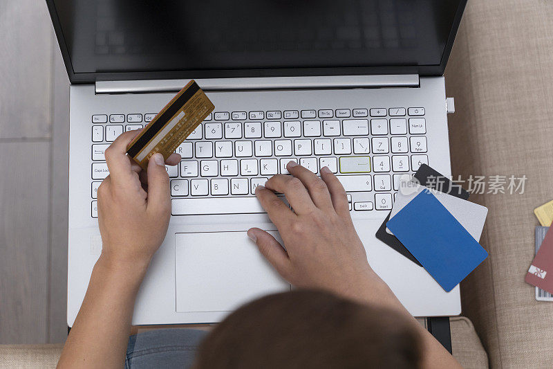 Top view of boy 's hands holding credit card near keyword of laptop, online shopping，